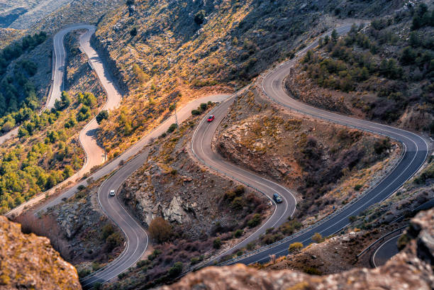 istock three cars drive along a mountainous road with sharp curves 2164029455