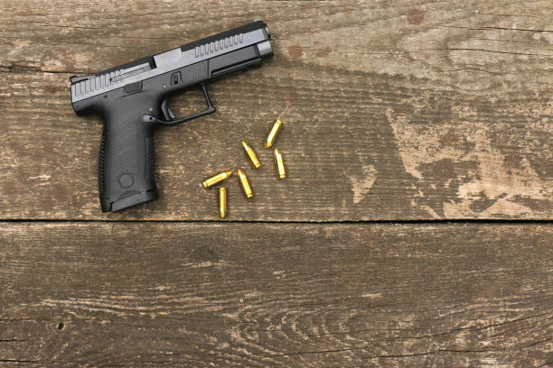 istock Modern automatic pistol and 9mm ammunition on old boards with an empty space in the middle. 2164029763