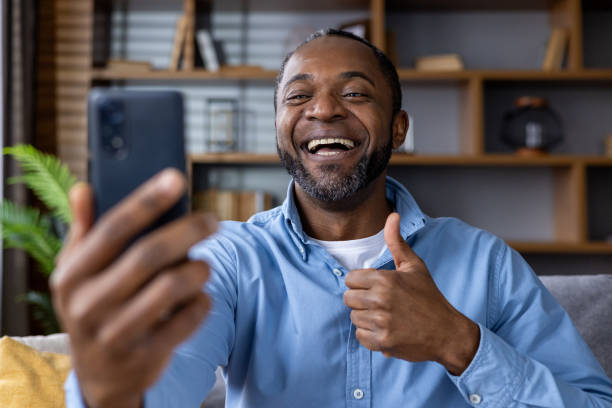 istock Smiling man making video call from home giving thumbs up gesture 2164030424