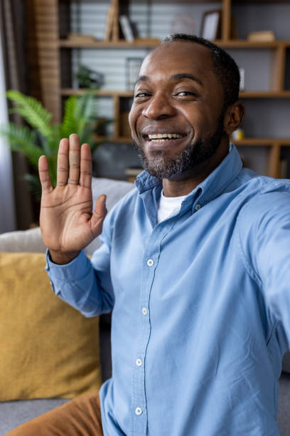 istock Smiling man waving and talking during a video call at home 2164030581