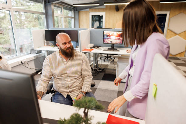 Successful young female leader in a suit with a pink shirt sitting in a modern glass office with a determined smile.Concept of business and the success of young people in modern online businesses