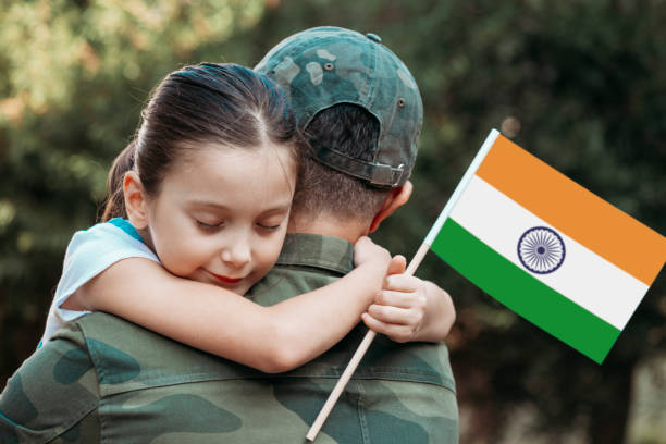 Little girl hugs the soldier father and holding Indian Flag.