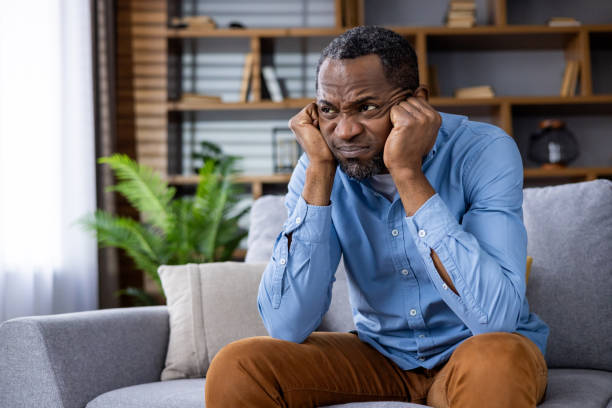istock Frustrated man sitting on a couch in a modern living room 2164032665