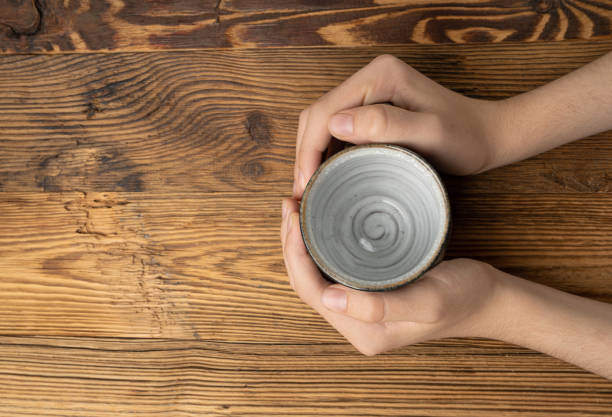 Hand Holds Cup, Empty Cup in Hands, Coffee Mug, Teacup Mockup, Cup in Arms on Wooden Table