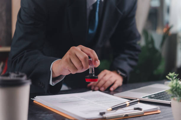 istock Business professional stamping a document, showcasing authority and validation. Suitable for legal, administrative, and business environments. 2164034623
