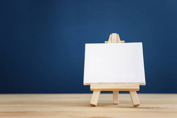 istock Small canvas on a stand, placed on a wooden table with blue background 2164034903