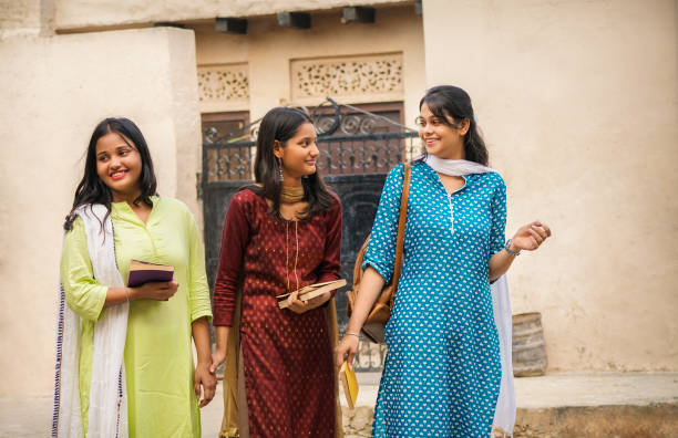 Cheerful rural Indian village teenage girl student going to college together. Portrait of cheerful rural Indian village teenage girl students walking together and going to college. They are wearing their traditional dress of north Indian (salwar, kameez and dupatta. Rural India and education concept. indian wedding stock pictures, royalty-free photos & images