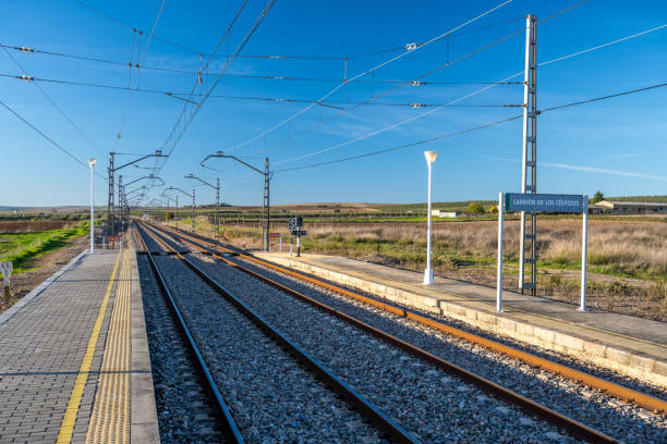 Empty railway station platform in Carrion de los Cespedes, Sevilla, Andalusia, Spain under a clear blue sky.