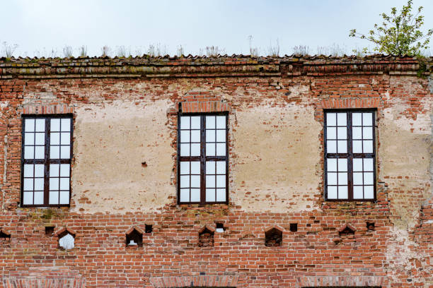 An abandoned, aged brick building with broken windows. The walls display wear and aging signs, revealing its distress