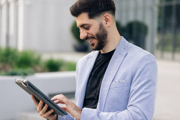 istock Happy face looking tablet screen outdoors. Elegant male chatting online with digital device outside. Businessman holding tablet in hands using business apps on tablet computer 2164041984