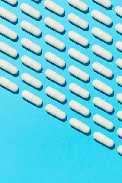 istock White capsule pills aligned diagonally on blue background 2164045807