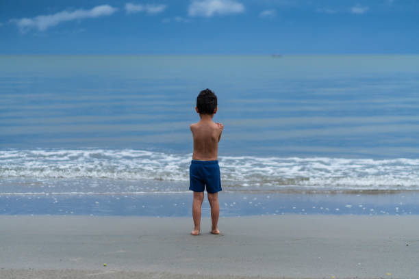 istock boy walking on the beach alone during a beautiful morning 2164047850