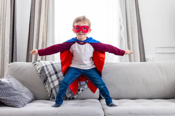 istock Boy in superhero costume on sofa 2164048315