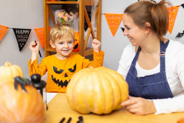 istock Child in pumpkin costume carving pumpkin 2164048502
