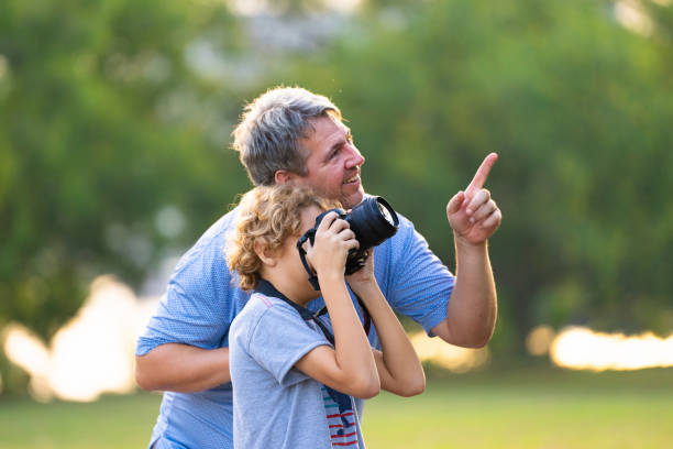Child learning to take photos. Kid photographer. Little boy watching birds and making images with professional camera. Parent teaching son to photograph wildlife. Young creative artist.