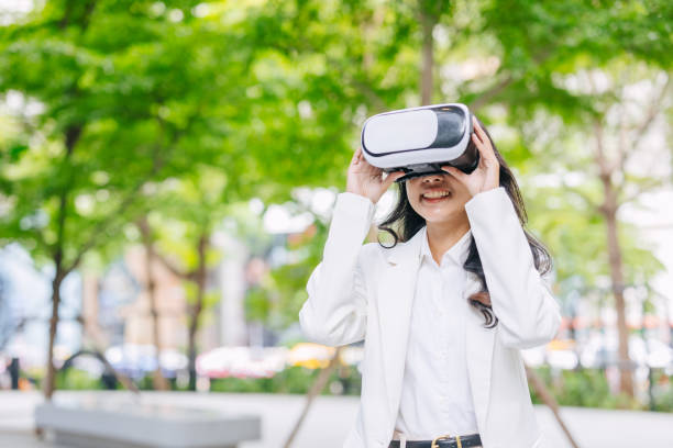 istock Modern business women using VR visual reality technology. People watching goggle glass gadget device outdoor green park. 2164054381
