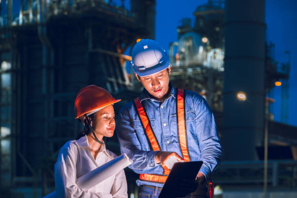 istock Petroleum refinery industry engineer night time working team. Power plant engineering workers teamwork plant evening survey support. 2164055457