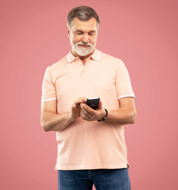 istock Mature man using smartphone. Handsome man with smart phone on pink background 2164060879