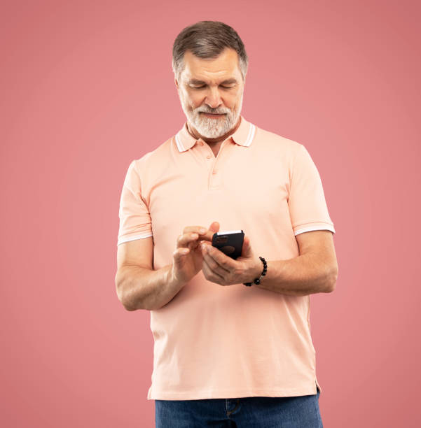 istock Mature man using smartphone. Handsome man with smart phone on pink background 2164060881