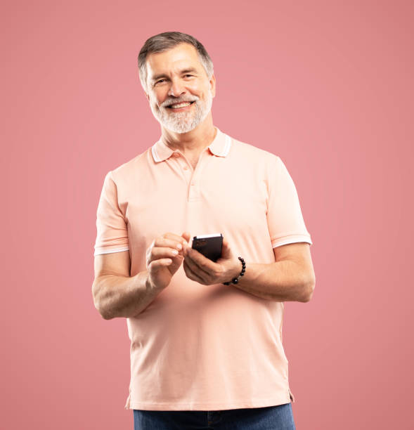istock Mature man using smartphone. Handsome man with smart phone on pink background 2164060911