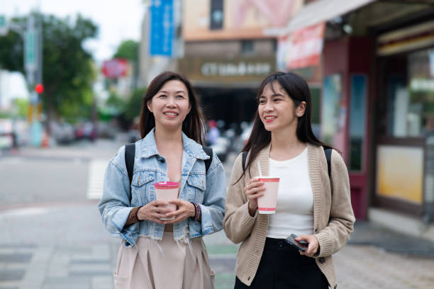 Two female travelers savor the delightful flavors of bubble tea while exploring the lively city streets of Taiwan.