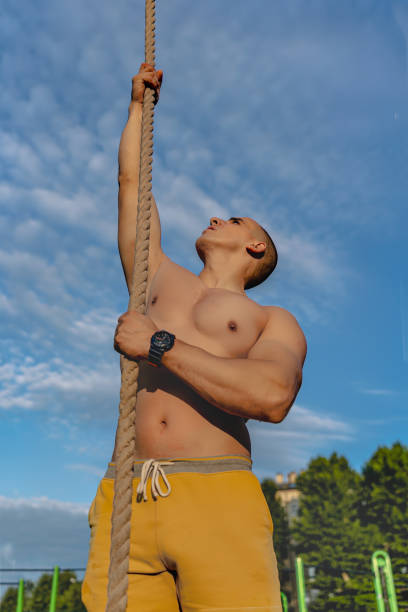 istock Young man engaging in strength training climbing a rope in a park 2164063487