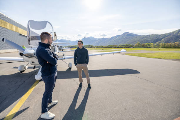 istock Two Men Conversing Near Light Aircraft at Airfield 2164063574