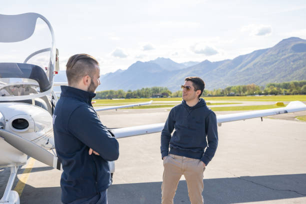 istock Two Men Conversing Near Light Aircraft at Airfield 2164063626