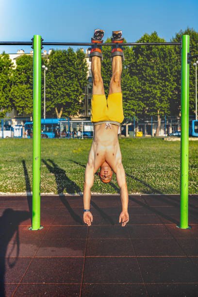 istock Young man practices upside down gymnastics on exercise bar in sunny park setting 2164064930