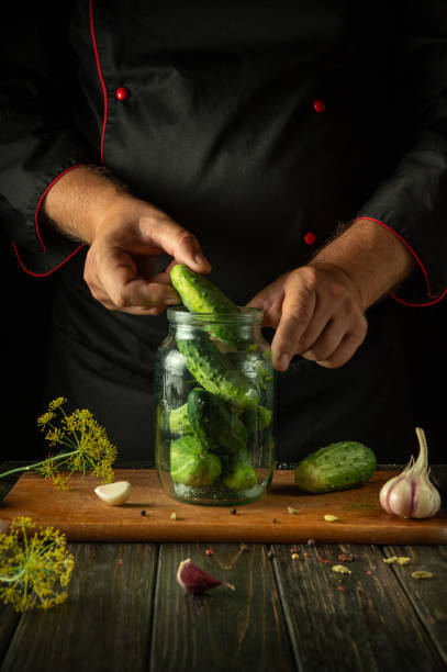 istock Hand filling a jar with cucumbers before canning with garlic and dill on the kitchen table. Concept of pickling cucumbers for long-term storage 2164065007