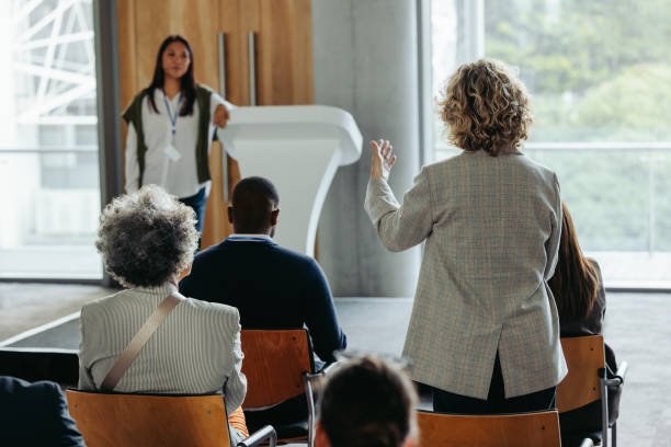 istock Business workshop with woman answering a question during formal presentation or talk 2164067021