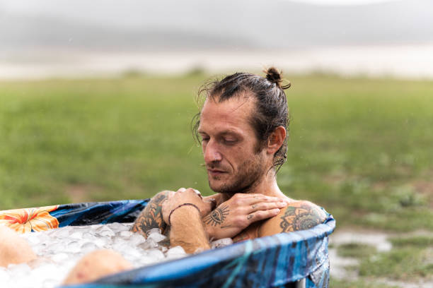Young man taking ice bath outdoors for muscle recovery after workout