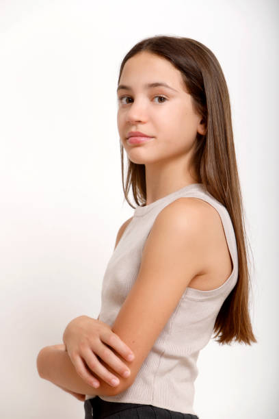 teenager with serious expression looking half-sideways at camera on light background