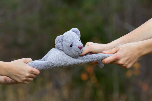 A childish quarrel. Two children share a toy - a teddy bear. Close-up of the hands that tear the bear cub.