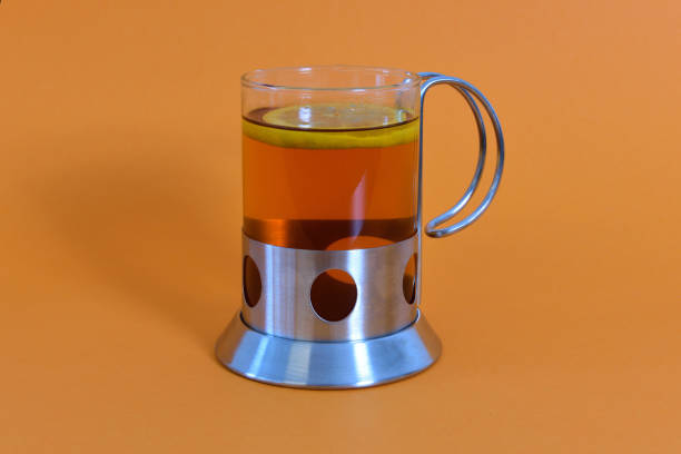 Black tea with lemon in a glass with holder photographed against a colorful background