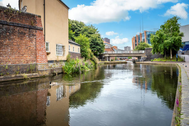 A photograph of the trendy New Islington waterfront in Ancoats, Greater Manchester, England. This stunning new residential development is one of the trendiest up and coming downtown residential districts in East Manchester. Modern apartments can be seen in the foreground alongside very expensive houseboats. In the background, converted Victorian mills dominate the skyline. A reminder of Manchester’s rich industrial heritage. The photograph was produced on a beautiful sunny afternoon.