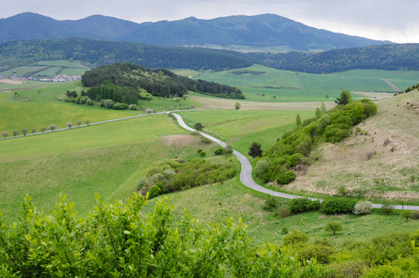 Idyllic rural landscape featuring rolling hills with sparse vegetation and a vivid blue sky, conveying tranquility and serenity.