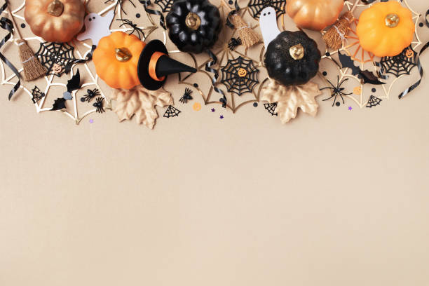 istock Halloween holiday frame with party decorations from pumpkins, bats, spider web and ghosts top view. Happy halloween greeting card on golden background. 2164080693
