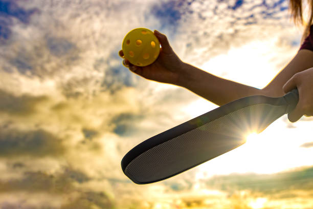 tenir la balle de pickleball et la raquette contre le ciel - pickleball photos et images de collection