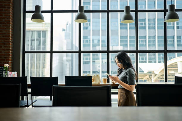istock Business executive standing by cafe table with smartphone 2164082610