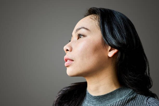 istock Pretty young woman looking away against grey background 2164082874