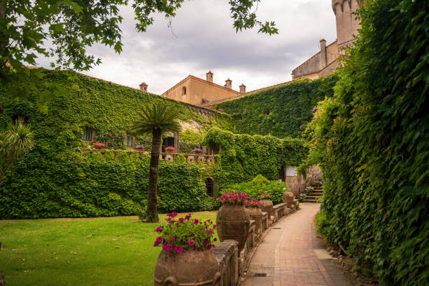 Ravello, Italy - June 20, 2024: Cimbrone villa view showcasing A picturesque courtyard featuring ivy-covered buildings, lush greenery, and a serene pathway. An ideal scene for relaxation and nature lovers.