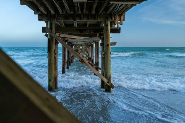 A wooden pier extending into the ocean waves, capturing the serene and dynamic coastal environment.
