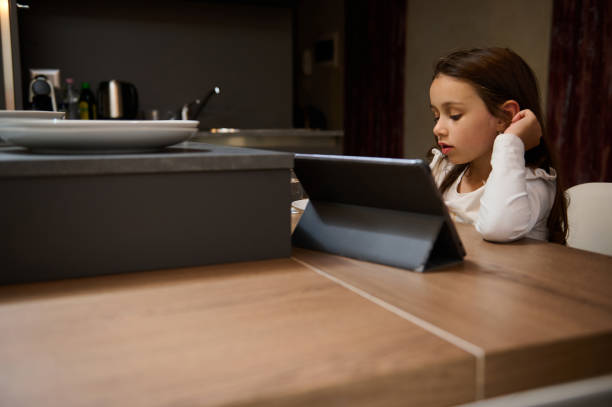 istock Young girl concentrating on tablet in kitchen, learning or enjoying digital activity 2164090762