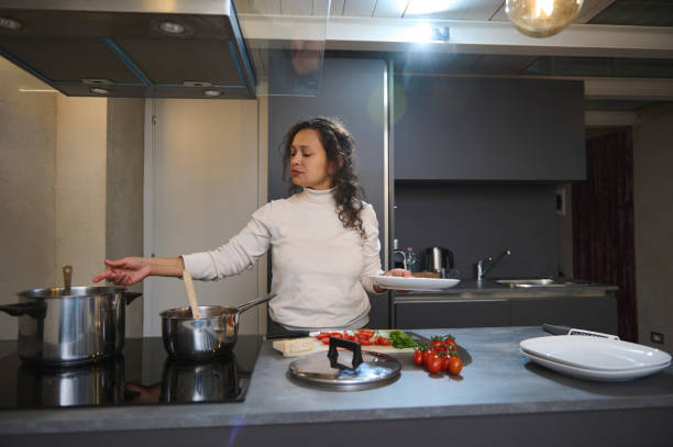 istock Woman cooking in modern kitchen while multitasking with different pots and fresh ingredients 2164090776