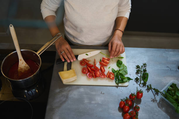 istock Person preparing fresh tomatoes and basil in a kitchen with cheese and tomato sauce 2164090782