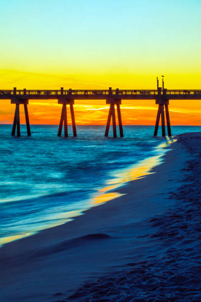Pensacola Beach, Florida pier reaches into the Gulf of Mexico at sunset in early December, Escambia County, in the western part of the Florida panhandle. Clear, colorful sky with very few clouds.