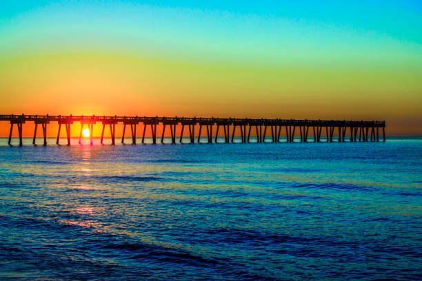 Pensacola Beach, Florida pier reaches into the Gulf of Mexico at sunrise in early December, Escambia County, in the western part of the Florida panhandle. Clear sky, no clouds.