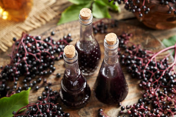 istock Three bottles black elder syrup with fresh elderberries on a wooden table 2164101799