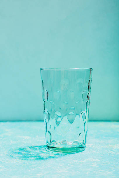 single Empty textured glass tumbler on blue background with space for text or copy